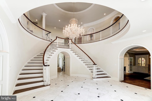 entrance foyer with light hardwood / wood-style floors, crown molding, a high ceiling, and a notable chandelier