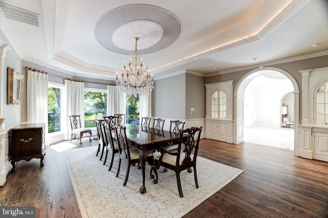 dining area featuring ornamental molding, a chandelier, a tray ceiling, dark hardwood / wood-style floors, and decorative columns