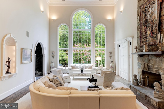 living room with hardwood / wood-style flooring, a fireplace, ornamental molding, and a high ceiling