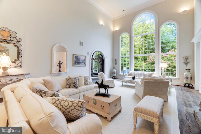 living room featuring light hardwood / wood-style floors, a towering ceiling, and ornamental molding