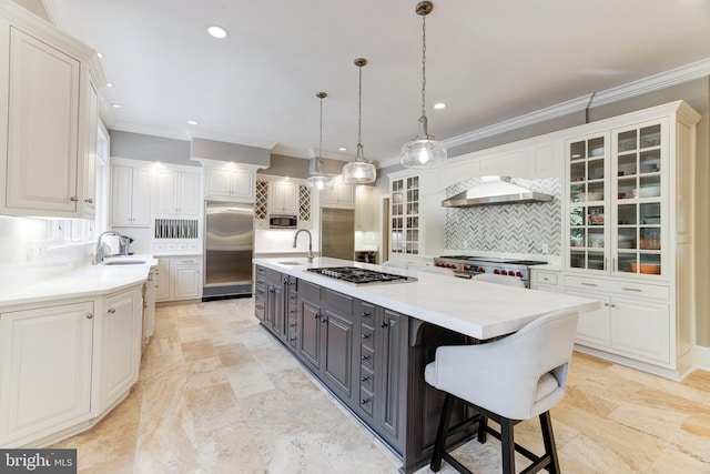 kitchen with white cabinets, decorative backsplash, stainless steel appliances, a center island with sink, and extractor fan