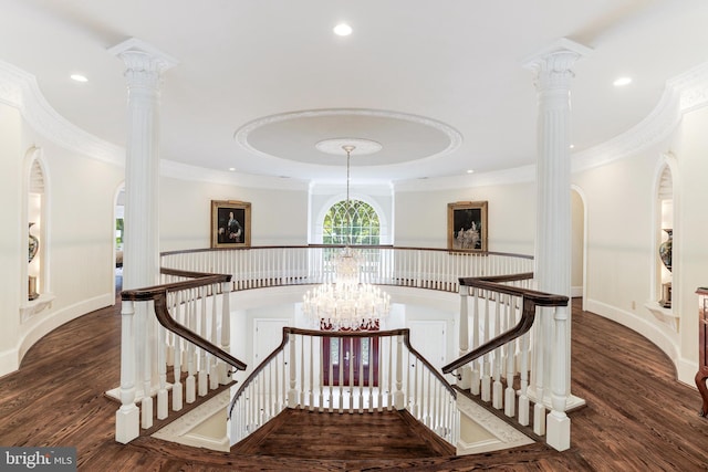 staircase with wood-type flooring, ornamental molding, a chandelier, and ornate columns