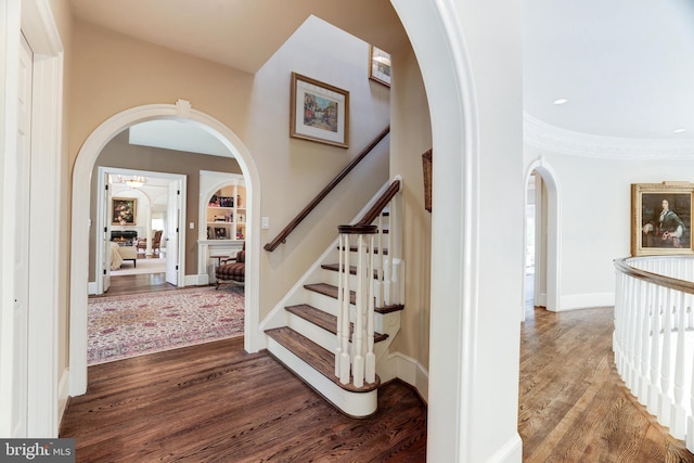 staircase with hardwood / wood-style floors and built in features