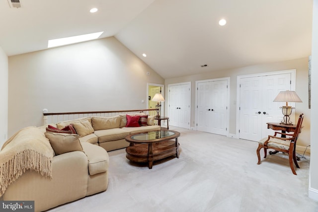 carpeted living room with lofted ceiling with skylight