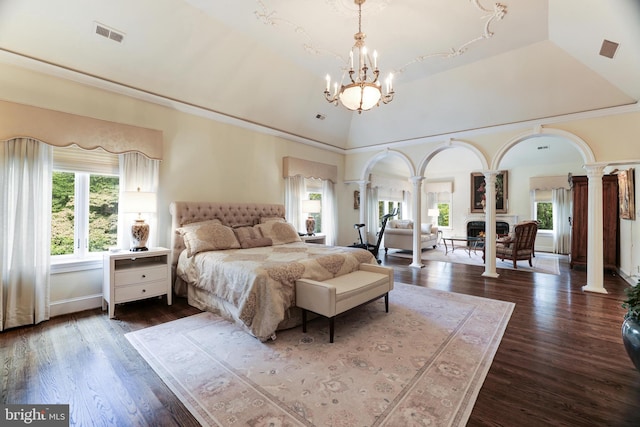 bedroom with an inviting chandelier, dark hardwood / wood-style floors, decorative columns, and high vaulted ceiling