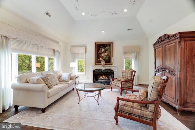 living room with high vaulted ceiling, a premium fireplace, plenty of natural light, and hardwood / wood-style floors