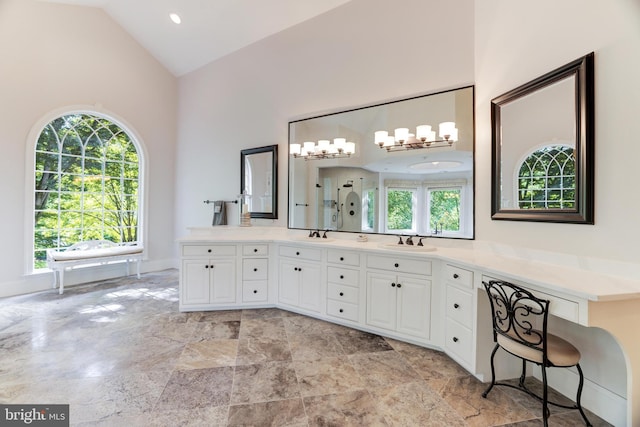 bathroom with a healthy amount of sunlight, vanity, and high vaulted ceiling