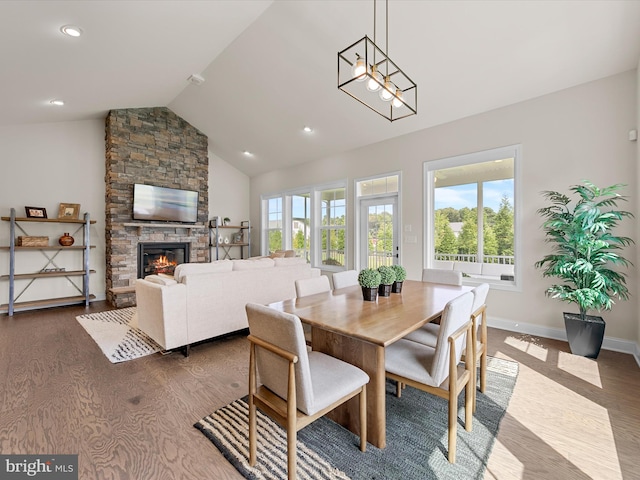 dining area featuring a fireplace, dark hardwood / wood-style flooring, high vaulted ceiling, and an inviting chandelier