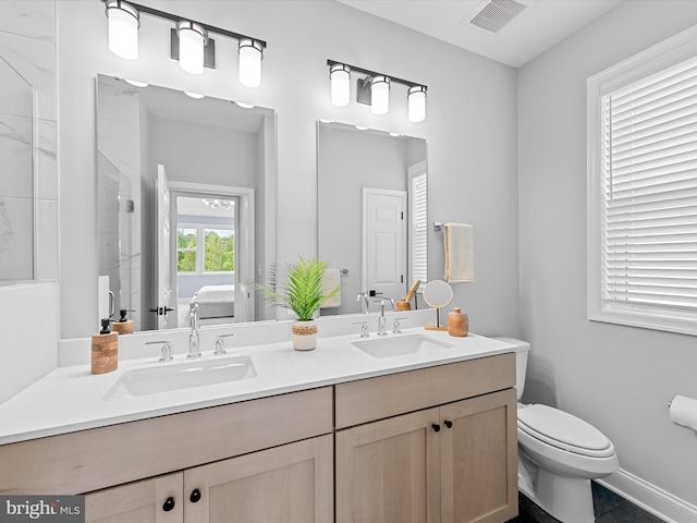 bathroom with vanity, toilet, tiled shower, and tile patterned flooring