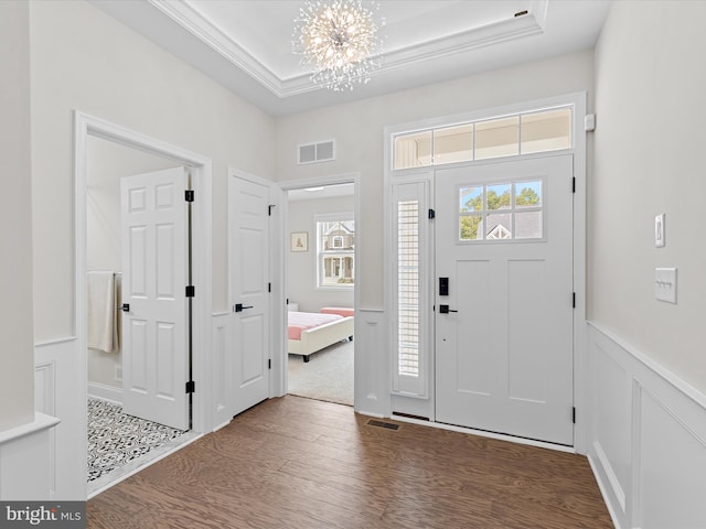 entryway featuring a tray ceiling, dark wood-type flooring, and a chandelier