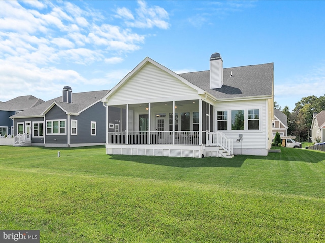 rear view of house featuring roof with shingles, a lawn, a chimney, and a sunroom