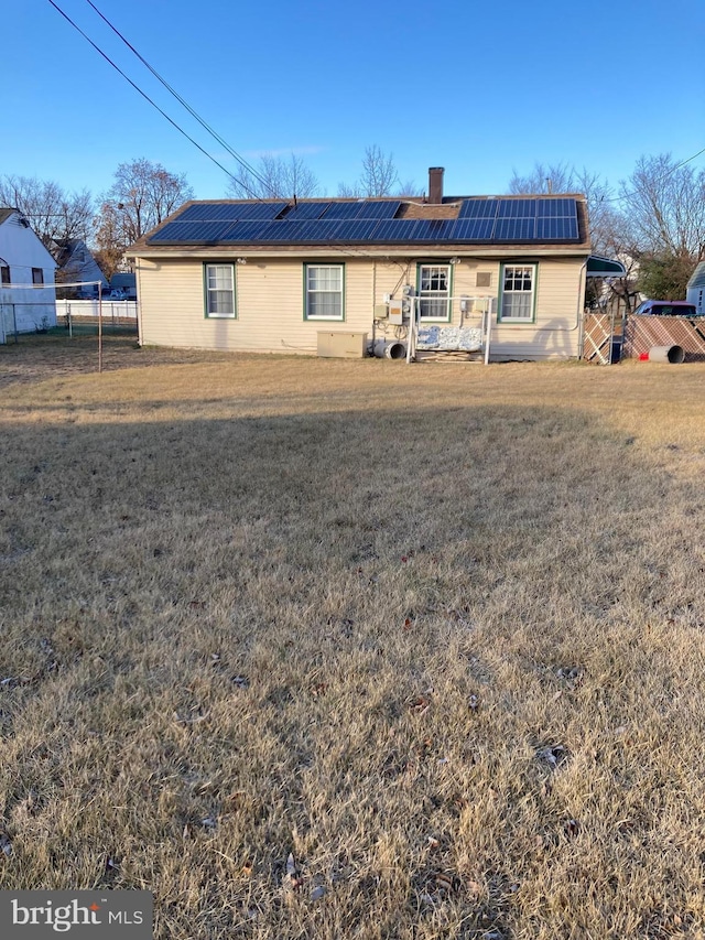 view of front of property with a front lawn and solar panels