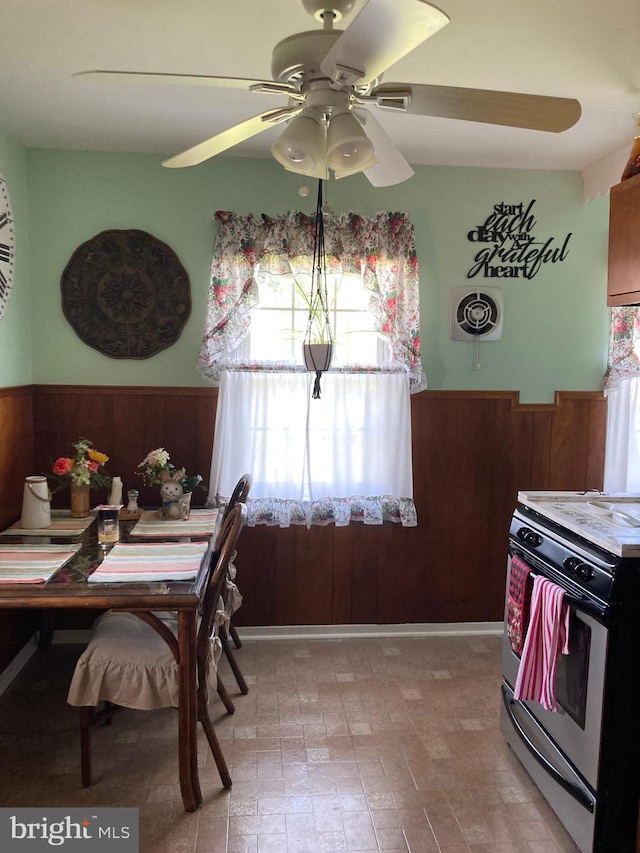 dining room featuring ceiling fan and wooden walls