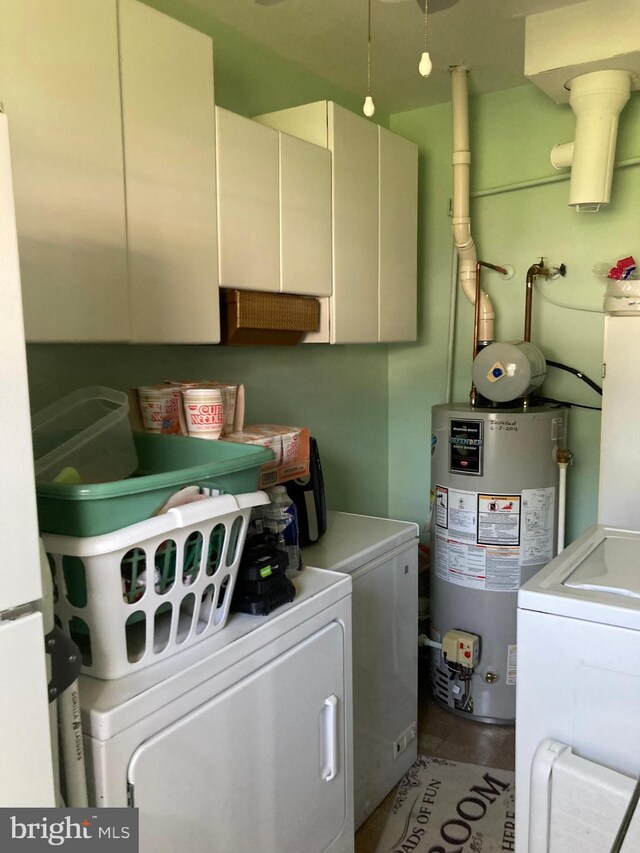 laundry room with cabinets, washer and dryer, and gas water heater