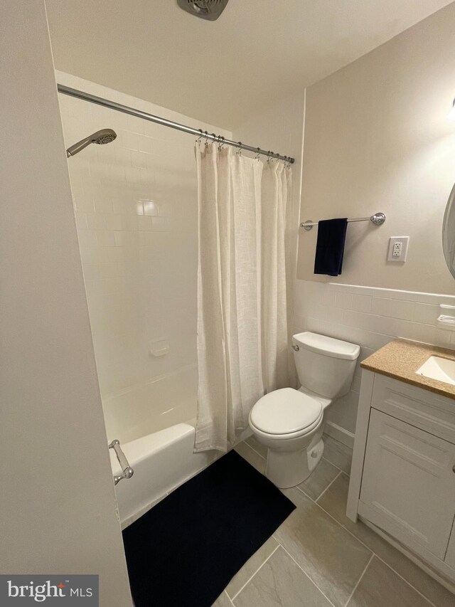 full bathroom with shower / tub combo, vanity, toilet, and tile walls