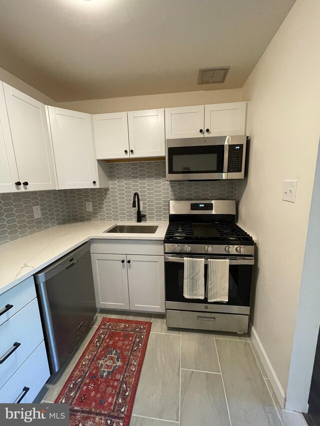 kitchen featuring tasteful backsplash, white cabinetry, sink, and stainless steel appliances