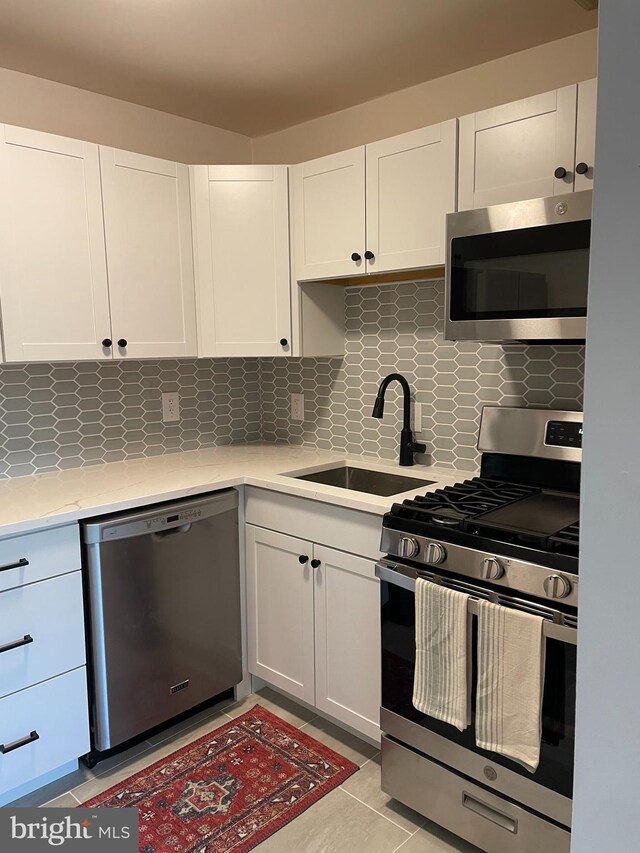 kitchen with stainless steel appliances, white cabinetry, and sink