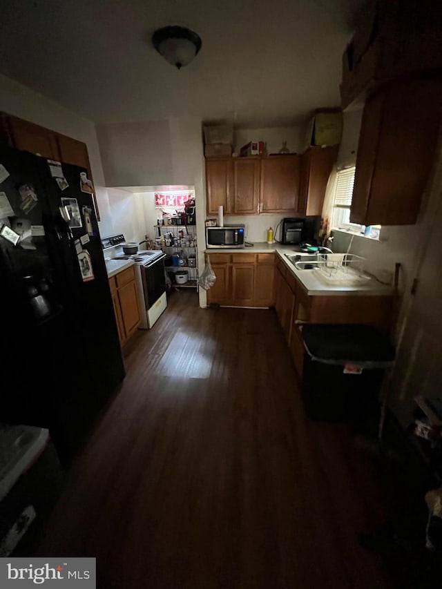 kitchen featuring dark hardwood / wood-style floors, sink, black fridge, and white electric stove