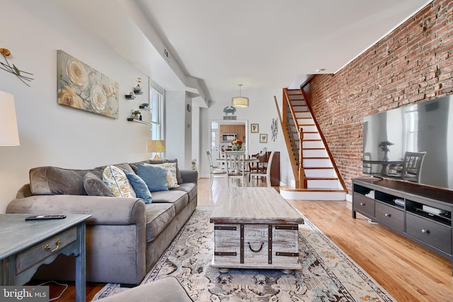 living room featuring light hardwood / wood-style floors, brick wall, and a healthy amount of sunlight