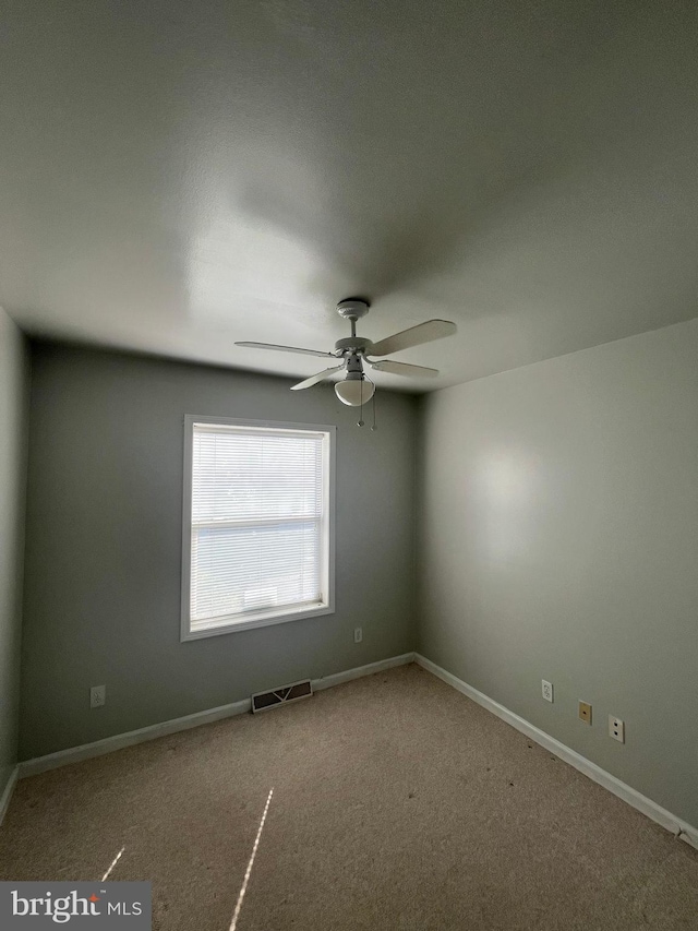 empty room featuring carpet, visible vents, ceiling fan, and baseboards