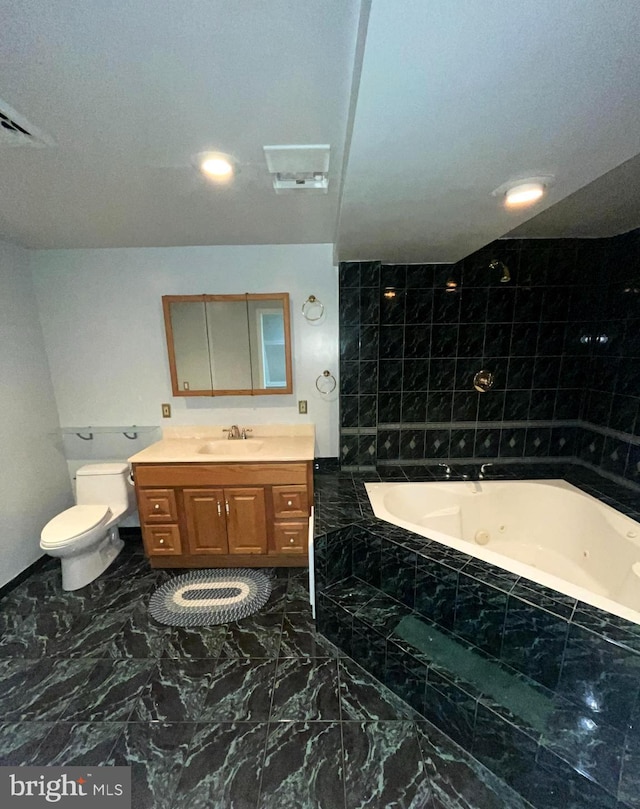 full bathroom featuring marble finish floor, tile walls, toilet, vanity, and a tub with jets