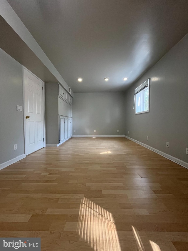 empty room featuring light wood finished floors, baseboards, and recessed lighting