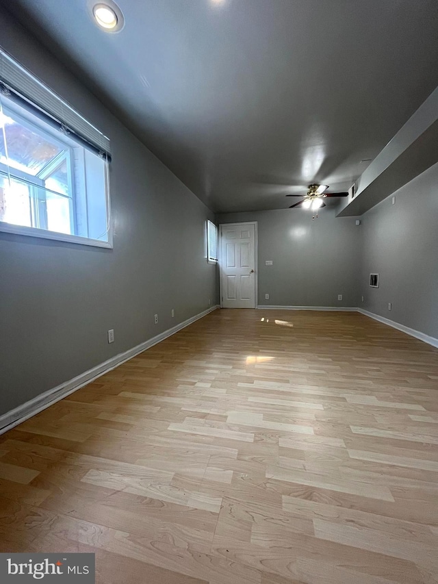 spare room with light wood-type flooring, a ceiling fan, and baseboards