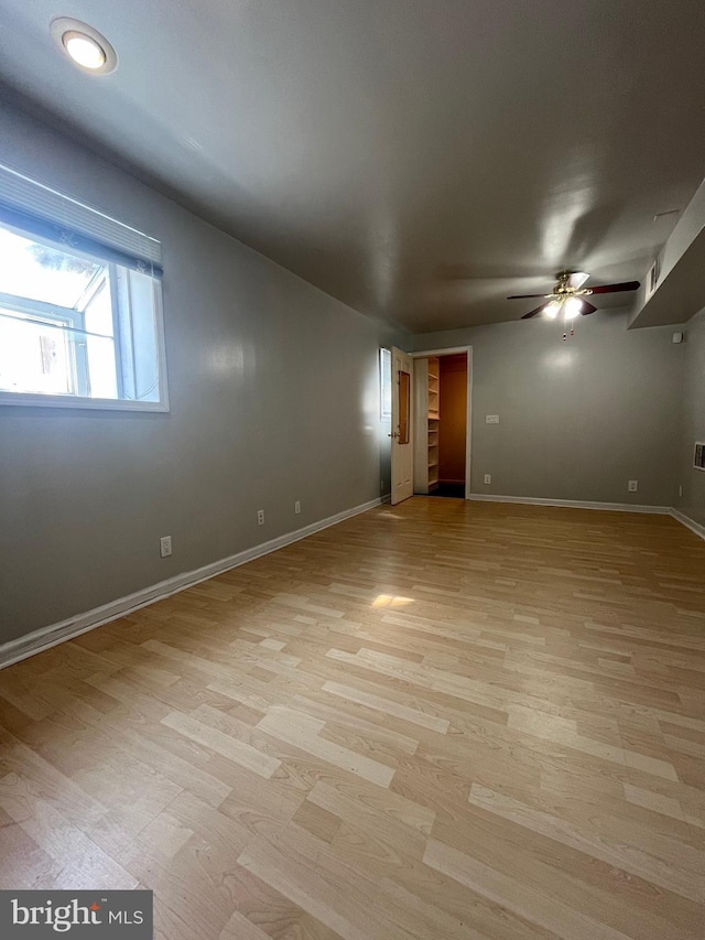 spare room featuring ceiling fan, light wood-style flooring, and baseboards