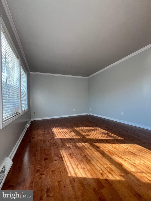 unfurnished room with baseboards, dark wood finished floors, visible vents, and crown molding