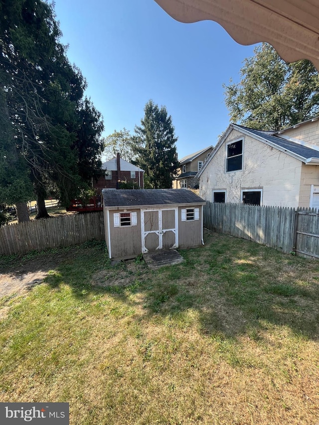 view of yard featuring a fenced backyard, an outdoor structure, and a storage shed