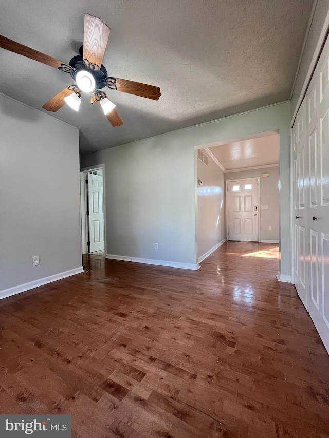 interior space with dark wood-style floors, a textured ceiling, and baseboards