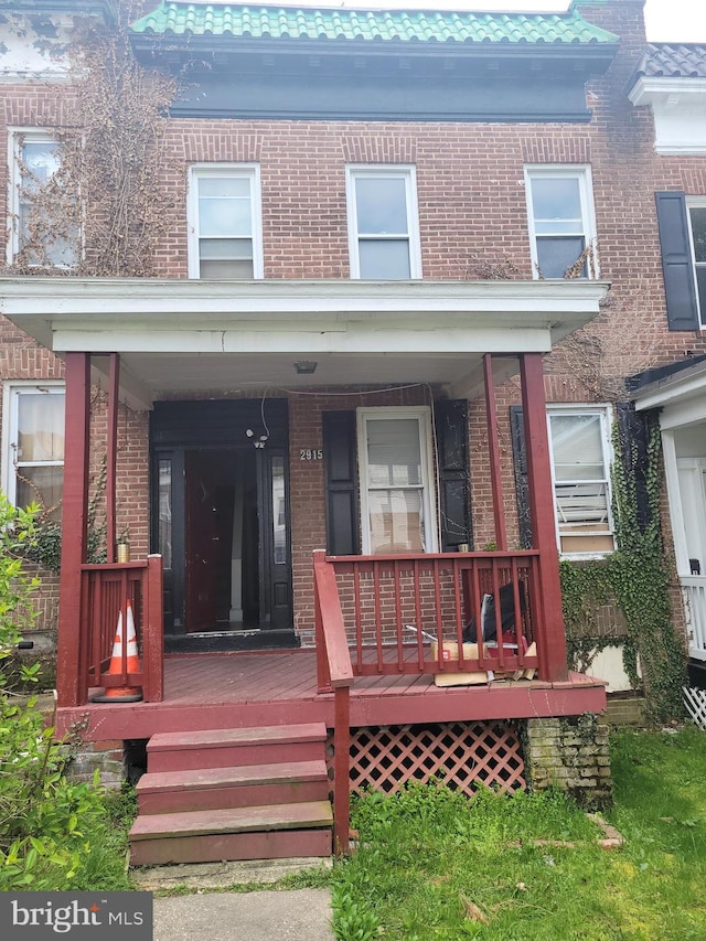 entrance to property with a porch and brick siding