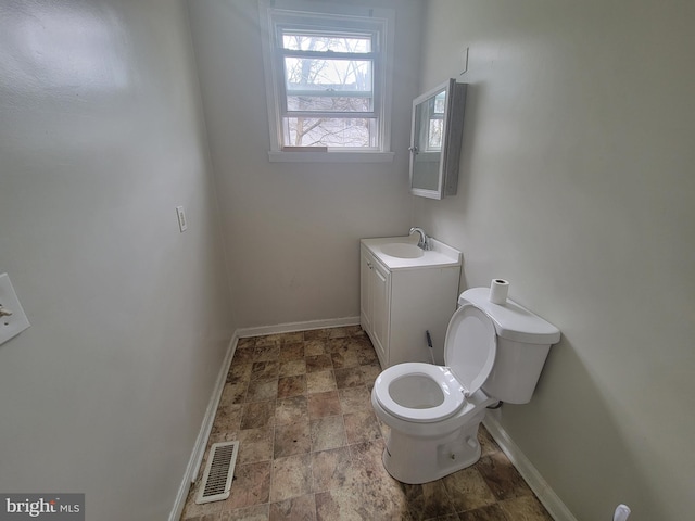 bathroom with toilet, vanity, visible vents, and baseboards