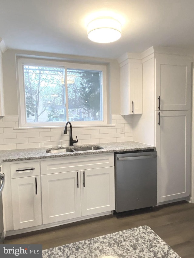 kitchen featuring white cabinetry, tasteful backsplash, light stone countertops, stainless steel dishwasher, and sink