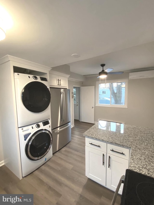 clothes washing area with ceiling fan, dark hardwood / wood-style flooring, and stacked washer and clothes dryer