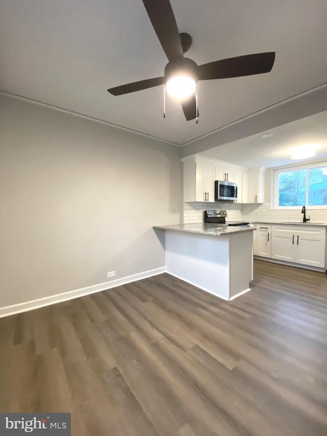 kitchen featuring appliances with stainless steel finishes, white cabinetry, backsplash, dark hardwood / wood-style floors, and kitchen peninsula