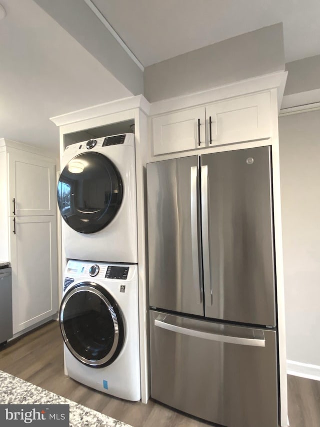 laundry room with dark wood-type flooring and stacked washer and clothes dryer