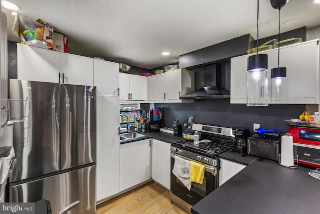 kitchen featuring appliances with stainless steel finishes, light hardwood / wood-style floors, sink, wall chimney range hood, and white cabinets