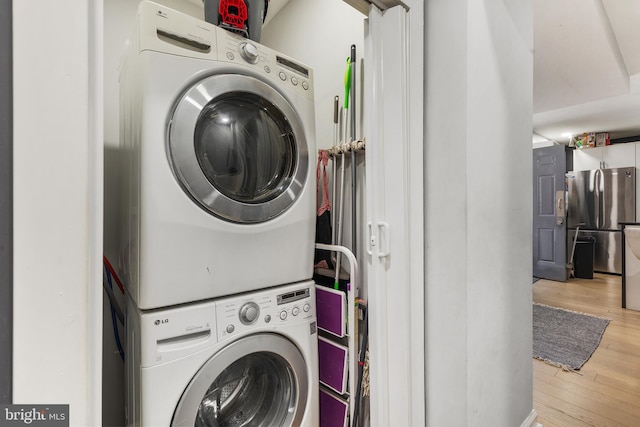 clothes washing area featuring stacked washer and clothes dryer and light wood-type flooring