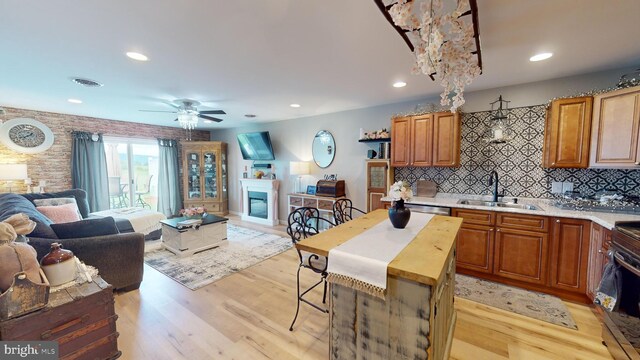 kitchen featuring decorative backsplash, sink, electric range, light wood-type flooring, and ceiling fan