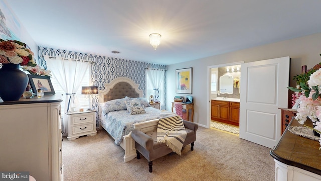 bedroom featuring a sink, connected bathroom, and light colored carpet