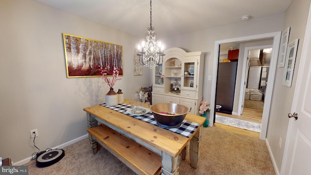 dining area with light carpet, baseboards, and a chandelier