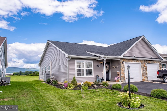 ranch-style home featuring a front lawn, central AC unit, and a garage