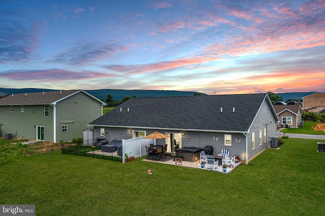 back house at dusk featuring a patio, central AC, and a yard