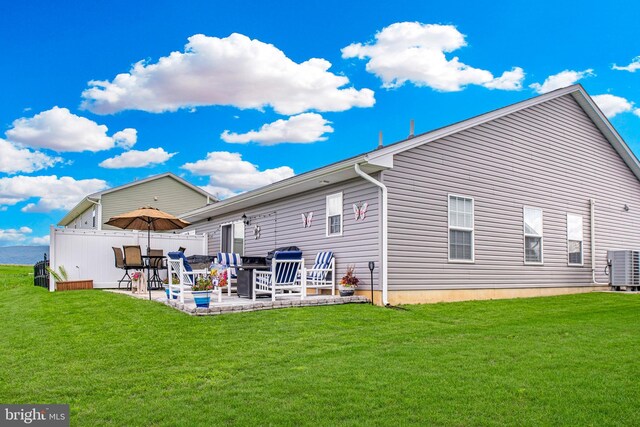 rear view of property with central air condition unit, a yard, and a patio