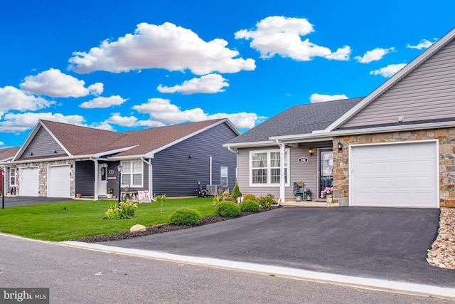 ranch-style home with a shingled roof, a front yard, stone siding, and driveway