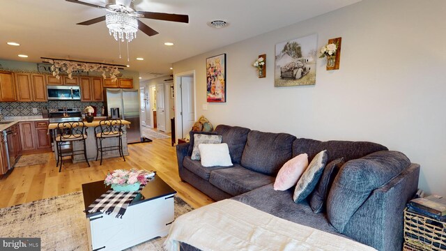 living room with light hardwood / wood-style floors, sink, and ceiling fan