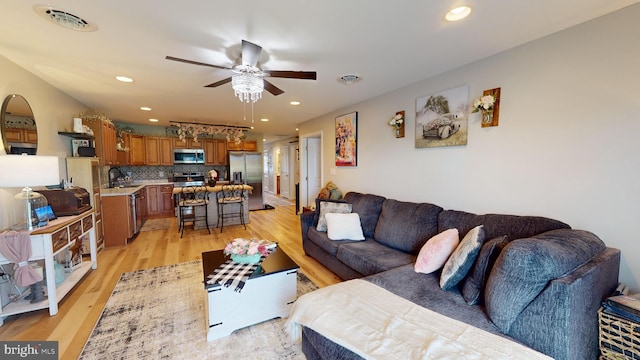 living room featuring a ceiling fan, light wood-type flooring, visible vents, and recessed lighting