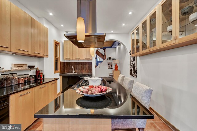 kitchen with island exhaust hood, a kitchen island, light tile patterned floors, and a kitchen breakfast bar