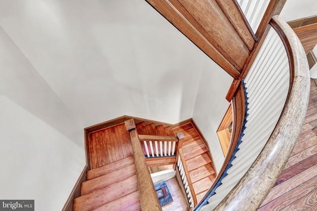 stairway with hardwood / wood-style floors and a high ceiling